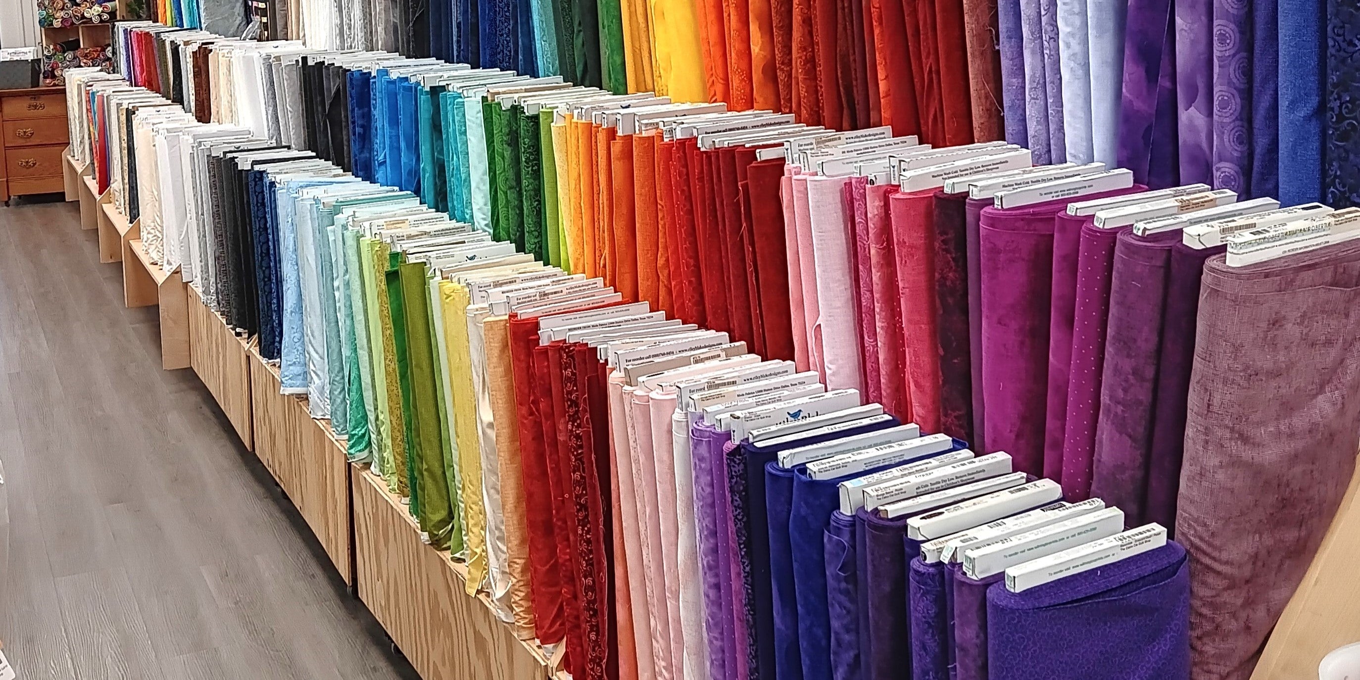 An image of colorful bolts of fabric along a wall